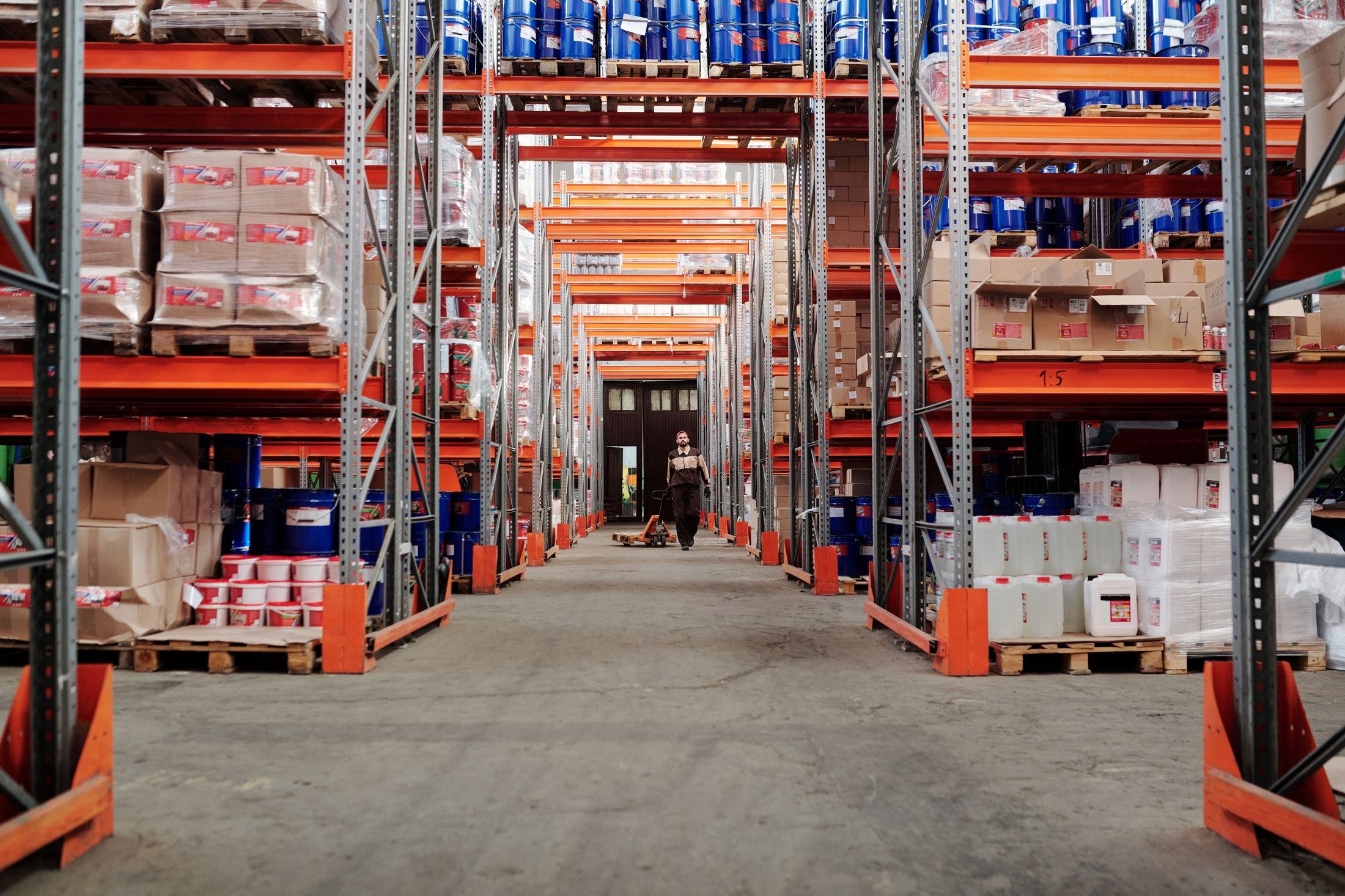 Tall warehouse racks loaded with palletized cartons, containers and goods.